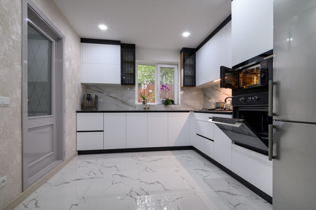A sleek, modern kitchen with white cabinets, a marble floor